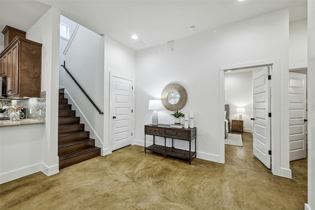 interior space with finished concrete flooring, baseboards, stairs, and recessed lighting