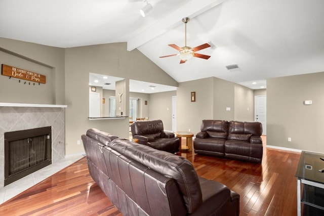 living room featuring a fireplace, wood-type flooring, vaulted ceiling with beams, and ceiling fan