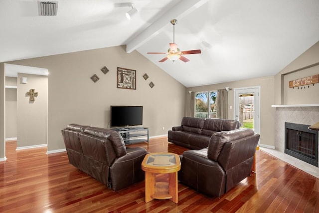 living room featuring a tiled fireplace, vaulted ceiling with beams, hardwood / wood-style flooring, and ceiling fan