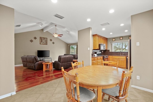 dining space featuring sink, vaulted ceiling with beams, light tile patterned floors, and ceiling fan