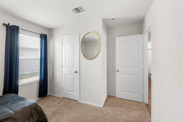 bedroom with visible vents, light colored carpet, and baseboards