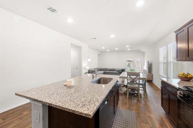 kitchen with a center island with sink, a sink, open floor plan, dark wood finished floors, and black gas range oven