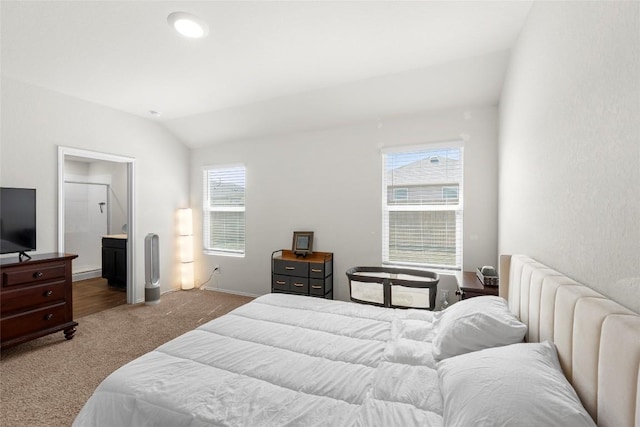 carpeted bedroom featuring ensuite bath and lofted ceiling