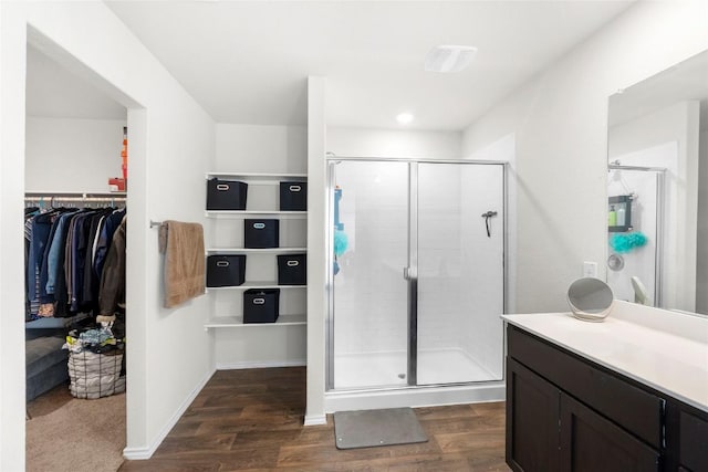 bathroom with a spacious closet, wood finished floors, and a shower stall