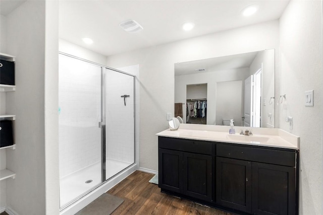 bathroom with visible vents, toilet, a stall shower, wood finished floors, and vanity