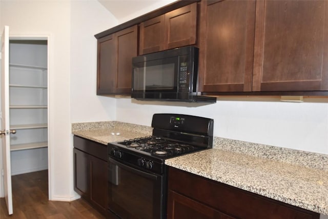 kitchen with dark brown cabinetry, light stone countertops, dark wood-type flooring, and black appliances