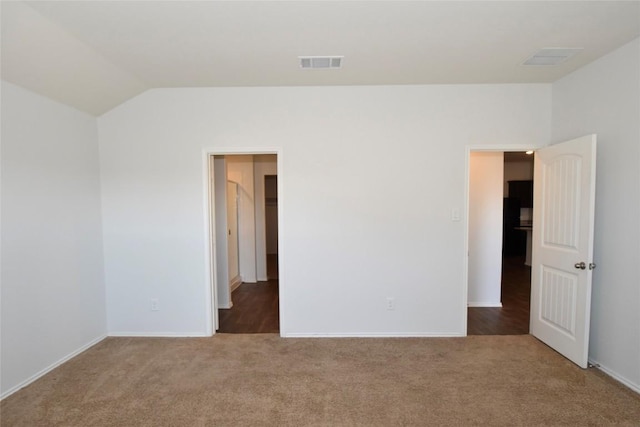 carpeted empty room featuring vaulted ceiling