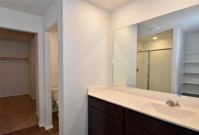 bathroom with toilet, vanity, and a shower with shower door