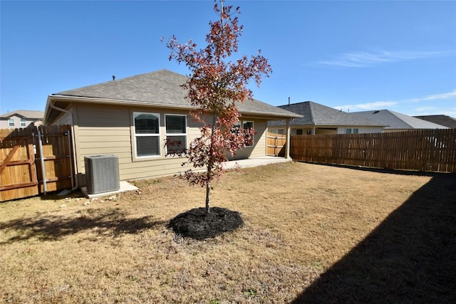 rear view of house with central AC unit and a lawn