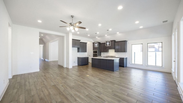 kitchen with a sink, wood finished floors, an island with sink, and open floor plan