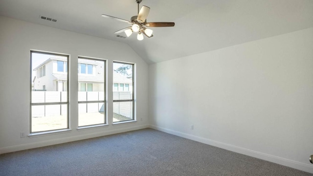 empty room featuring ceiling fan, vaulted ceiling, baseboards, and light carpet