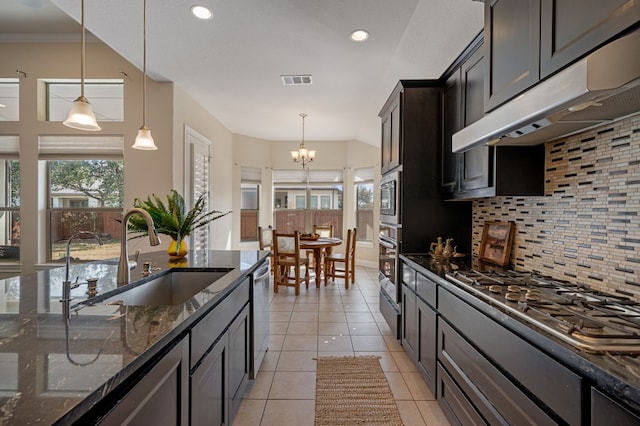 kitchen featuring appliances with stainless steel finishes, tasteful backsplash, sink, dark stone countertops, and hanging light fixtures