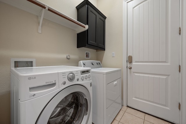 laundry room with cabinets, light tile patterned floors, and washer and clothes dryer