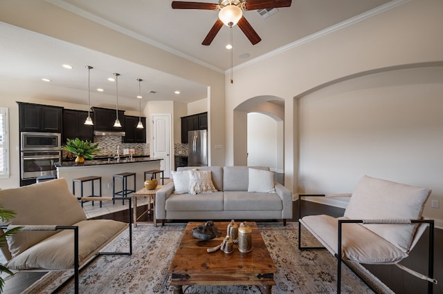 living room featuring sink, ornamental molding, and ceiling fan