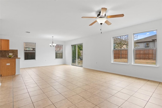 unfurnished living room featuring light tile patterned flooring, ceiling fan with notable chandelier, and a wealth of natural light