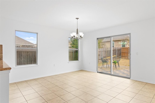 spare room with plenty of natural light, baseboards, and a chandelier