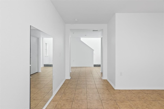 hallway featuring light tile patterned floors, visible vents, and baseboards