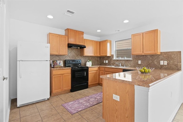 kitchen featuring light tile patterned floors, a peninsula, freestanding refrigerator, under cabinet range hood, and black range oven