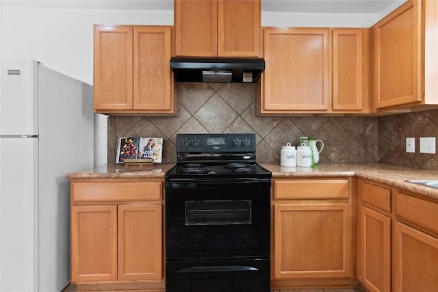 kitchen featuring under cabinet range hood, tasteful backsplash, black range with electric stovetop, and freestanding refrigerator