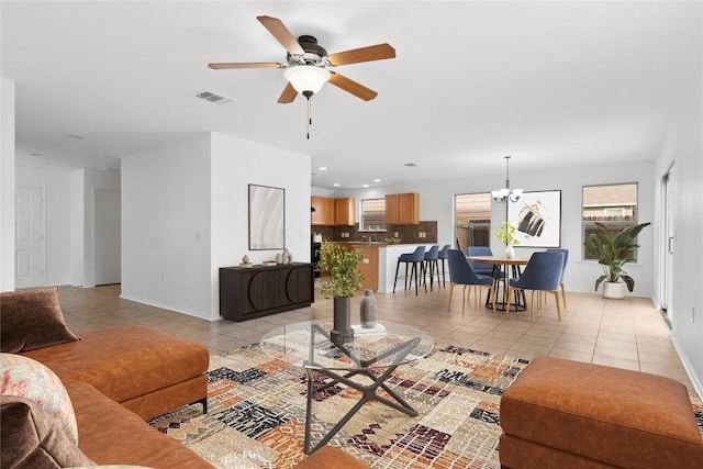 tiled living room featuring ceiling fan with notable chandelier