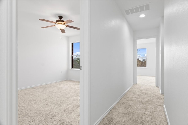 hallway with a wealth of natural light and light carpet