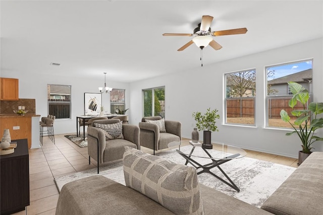 living room featuring light tile patterned flooring, visible vents, ceiling fan with notable chandelier, and baseboards