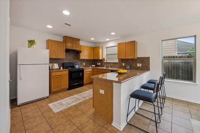 11009 Roderick Lawson Ln, Austin, TX 78754 - kitchen featuring black appliances, backsplash, under cabinet range hood, a peninsula, and a breakfast bar area