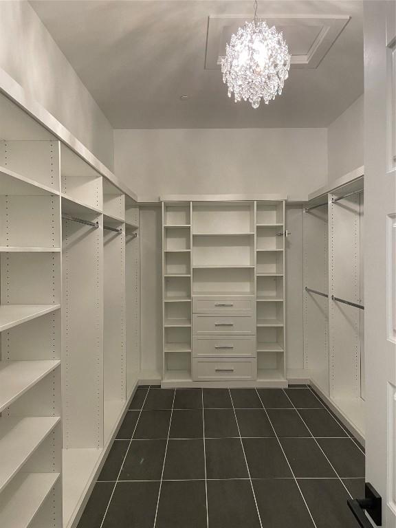 spacious closet featuring dark tile patterned flooring and a chandelier