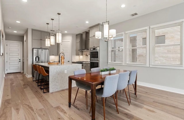 dining area featuring a notable chandelier, plenty of natural light, sink, and light wood-type flooring