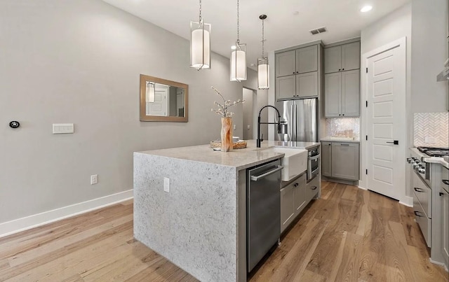 kitchen featuring gray cabinets, dishwasher, and a kitchen island with sink