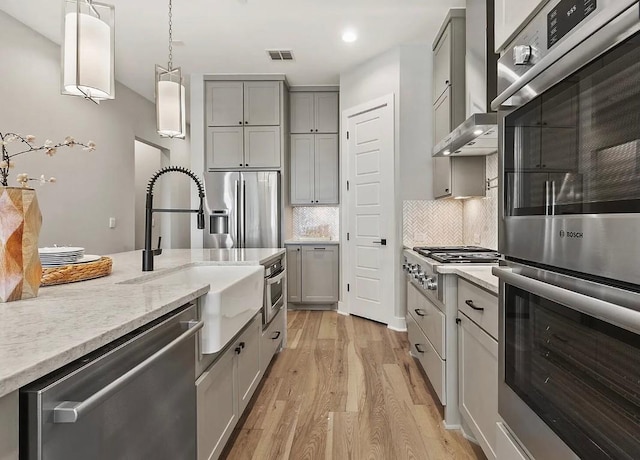 kitchen featuring appliances with stainless steel finishes, gray cabinets, sink, and hanging light fixtures