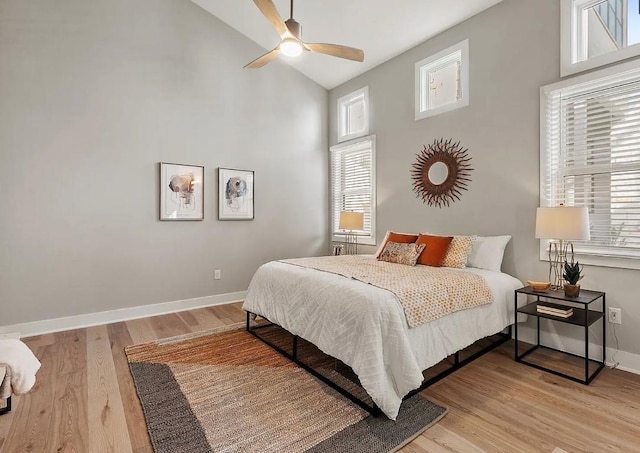 bedroom with ceiling fan, high vaulted ceiling, and light wood-type flooring