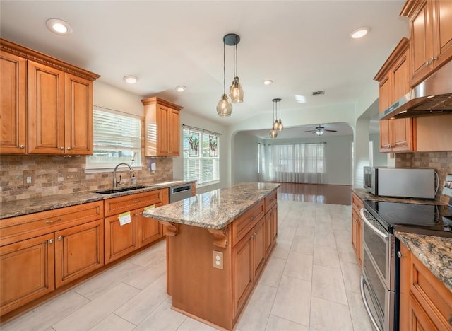 kitchen with a kitchen island, appliances with stainless steel finishes, decorative light fixtures, sink, and ceiling fan