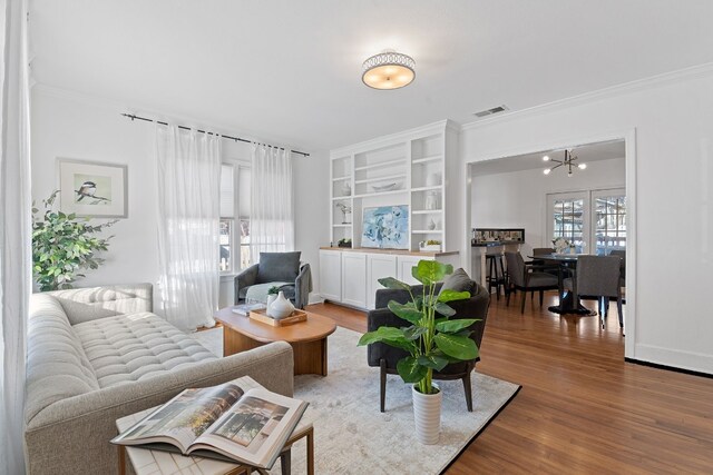 living room featuring hardwood / wood-style flooring, ornamental molding, and plenty of natural light