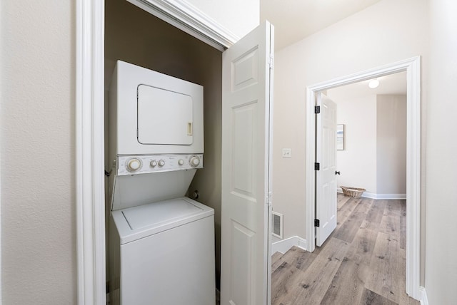 laundry room featuring stacked washer / dryer and light wood-type flooring