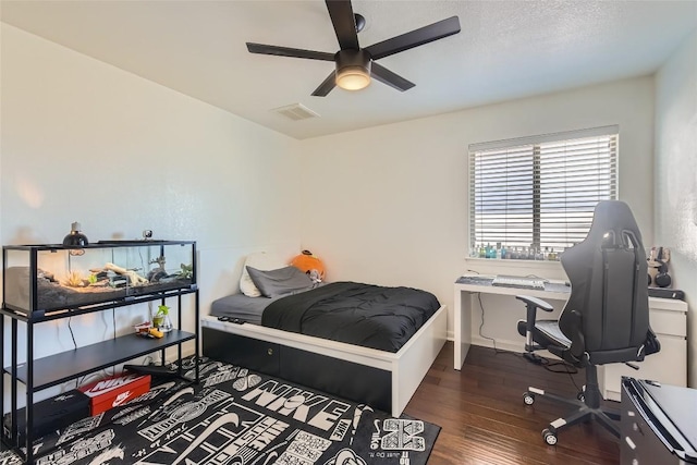 bedroom with a textured ceiling, dark wood-type flooring, and ceiling fan