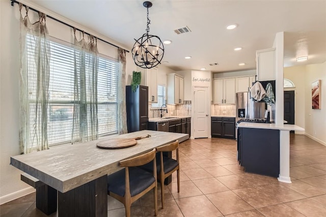 kitchen featuring appliances with stainless steel finishes, decorative light fixtures, white cabinetry, sink, and a center island