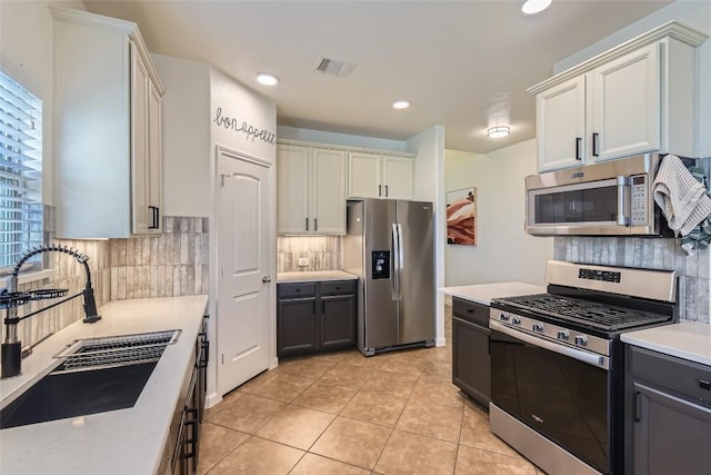 kitchen featuring sink, white cabinets, backsplash, light tile patterned floors, and stainless steel appliances