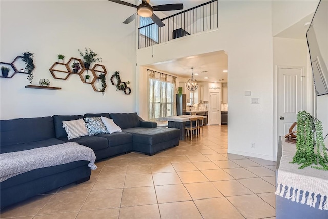 tiled living room with a towering ceiling and ceiling fan with notable chandelier