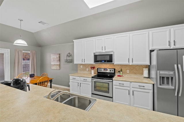 kitchen with sink, stainless steel appliances, white cabinets, decorative light fixtures, and vaulted ceiling