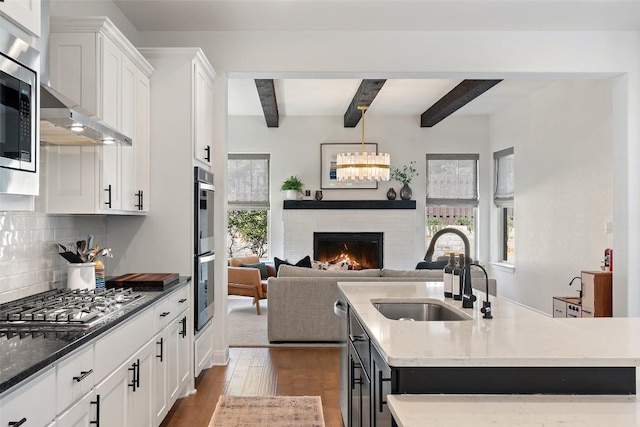 kitchen featuring appliances with stainless steel finishes, sink, a center island with sink, and white cabinets