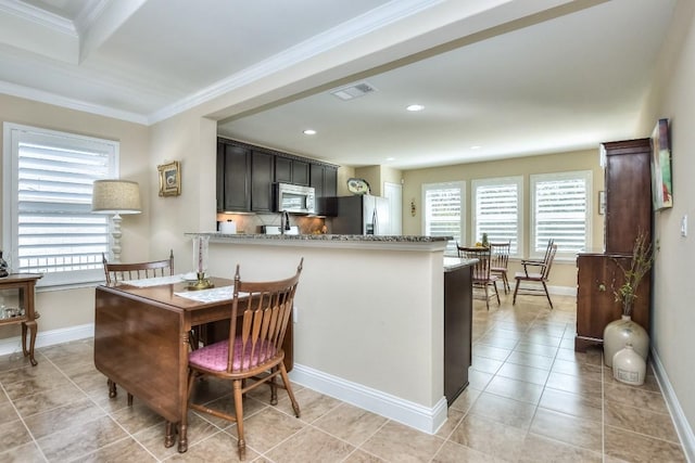 kitchen with light stone counters, light tile patterned floors, ornamental molding, appliances with stainless steel finishes, and backsplash