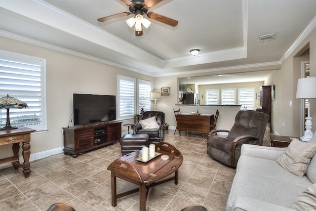 tiled living room featuring crown molding, a tray ceiling, and ceiling fan