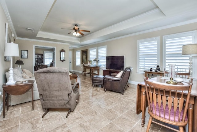 living room with crown molding, light tile patterned floors, a tray ceiling, and ceiling fan