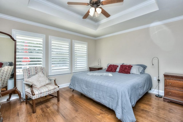 bedroom with wood-type flooring, crown molding, and a tray ceiling