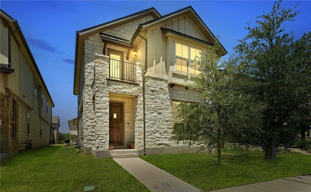 view of front of house with a balcony and a lawn