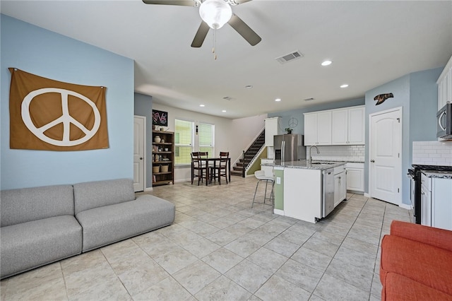kitchen with white cabinetry, appliances with stainless steel finishes, a kitchen island with sink, and a breakfast bar area