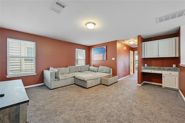 carpeted living room with a wealth of natural light and built in desk