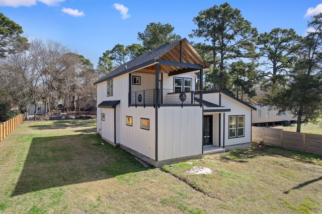 back of property with a yard and a balcony