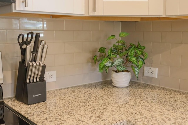 interior details with white cabinetry and light stone countertops